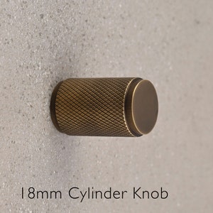 May include: A 18mm brass cylinder knob with a diamond pattern. The knob is a hardware item for furniture or doors.