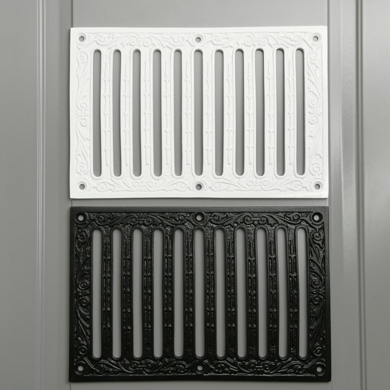 May include: Two decorative vent covers, one white and one black, with a traditional design. Both covers have a rectangular shape and feature a series of vertical bars with decorative details.