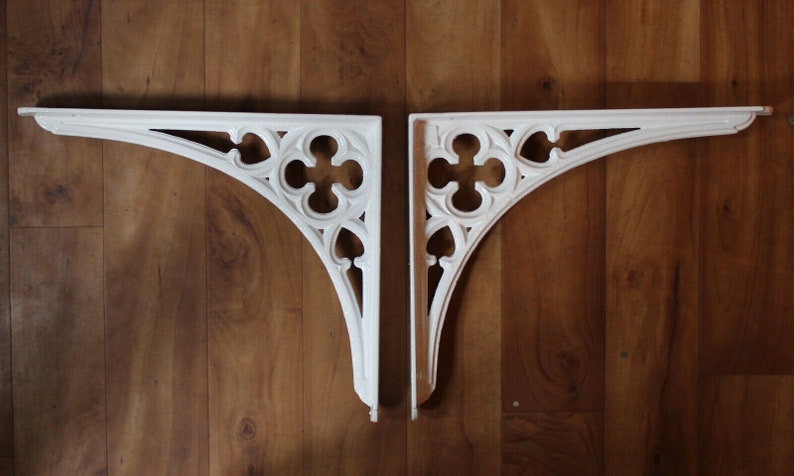 Puede incluir: Dos soportes de estante de madera blancos, decorativos, ornamentados, de estilo g&oacute;tico.