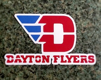May include: A red and white letter "D" with a blue and white wing design. The text "DAYTON FLYERS" is below the letter.