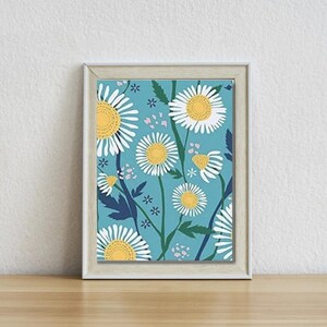 May include: A framed print featuring a blue background with white daisies and yellow centers. The daisies are arranged in a repeating pattern and are surrounded by small white and pink flowers.