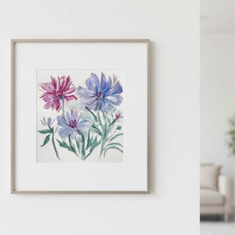 Puede incluir: Pintura a la acuarela de flores azules y moradas con hojas verdes. La obra de arte est&aacute; enmarcada en un marco gris claro con un passe-partout blanco. La pintura se exhibe en una pared blanca.