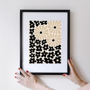 May include: A framed print with a black and beige floral pattern. The print features a repeating pattern of black flowers on a beige background.