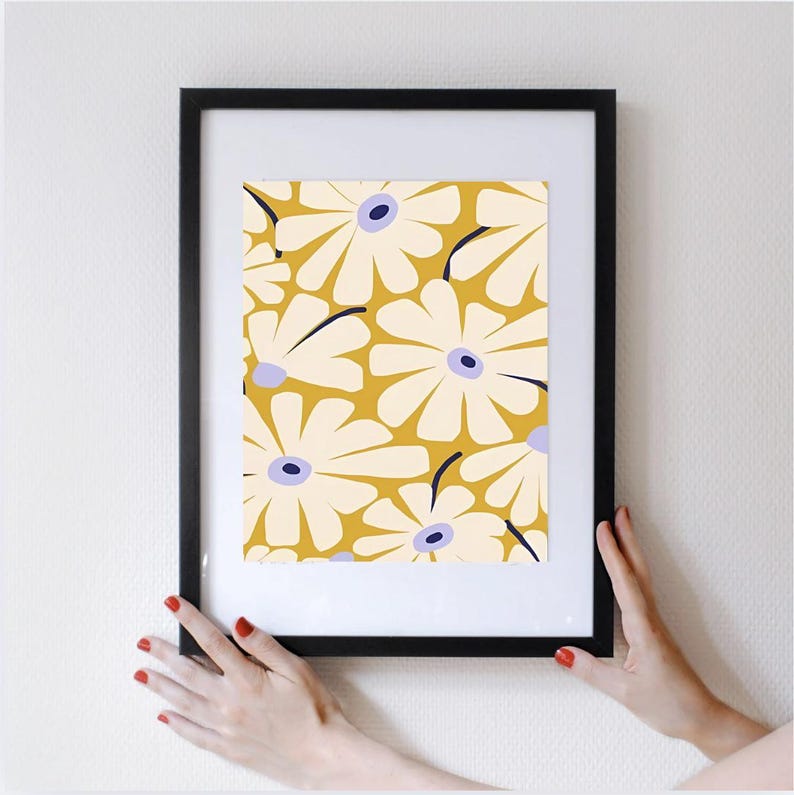 May include: A framed print with a pattern of white flowers with purple centers on a yellow background.