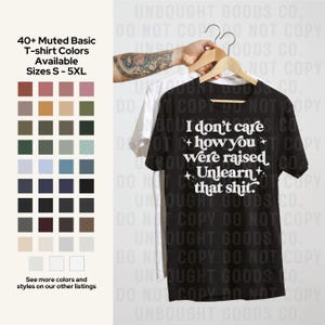 May include: Black t-shirt with the text "I don't care how you were raised. Unlearn that shit." displayed in white. A white t-shirt is behind it. The image also shows a colour chart with 40+ muted basic t-shirt colours available in sizes S-5XL.