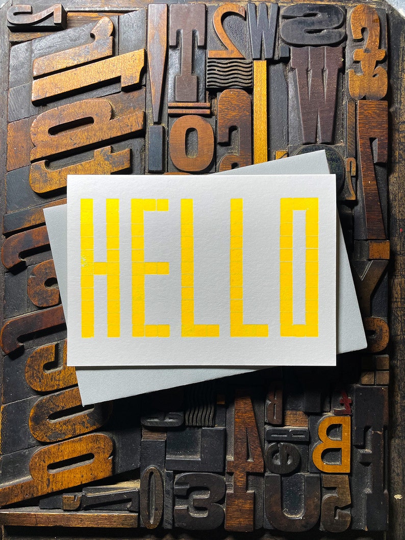 A card to just say HELLO and send to family and your friends.  
Made from a grid of square wooden type blocks. Printed using fluorescent yellow ink with a deep impression print. Luxurious Colorplan Pristine White thick 350gsm double-sided card.