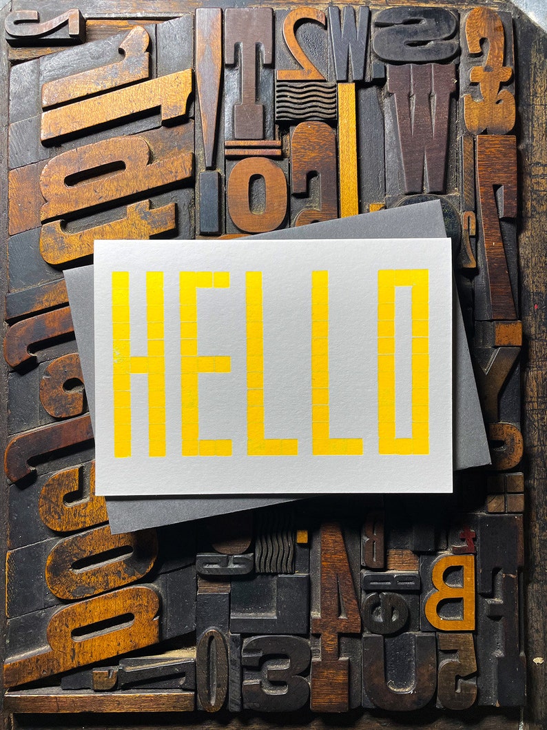 A card to just say HELLO and send to family and your friends.  
Made from a grid of square wooden type blocks. Printed using fluorescent yellow ink with a deep impression print. Luxurious Colorplan Pristine White thick 350gsm double-sided card.