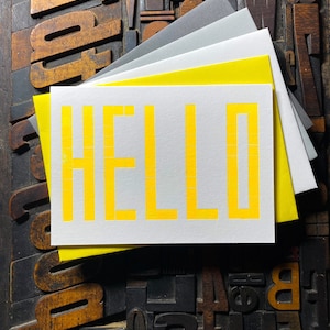 A card to just say HELLO and send to family and your friends.  
Made from a grid of square wooden type blocks. Printed using fluorescent yellow ink with a deep impression print. Luxurious Colorplan Pristine White thick 350gsm double-sided card.