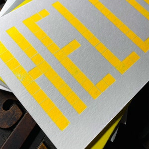 A card to just say HELLO and send to family and your friends.  
Made from a grid of square wooden type blocks. Printed using fluorescent yellow ink with a deep impression print. Luxurious Colorplan Pristine White thick 350gsm double-sided card.