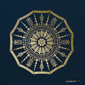 May include: Gold stencil with a circular design featuring a floral motif and intricate details. The stencil is on a dark blue background.