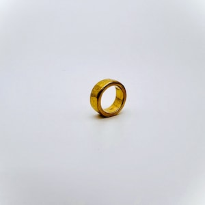 May include: A gold-colored ring with a textured surface.