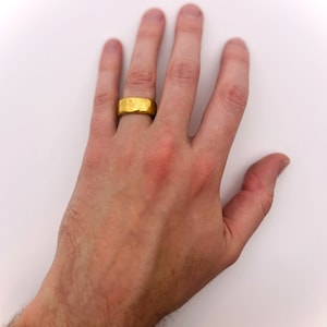May include: A gold band ring with a textured surface.