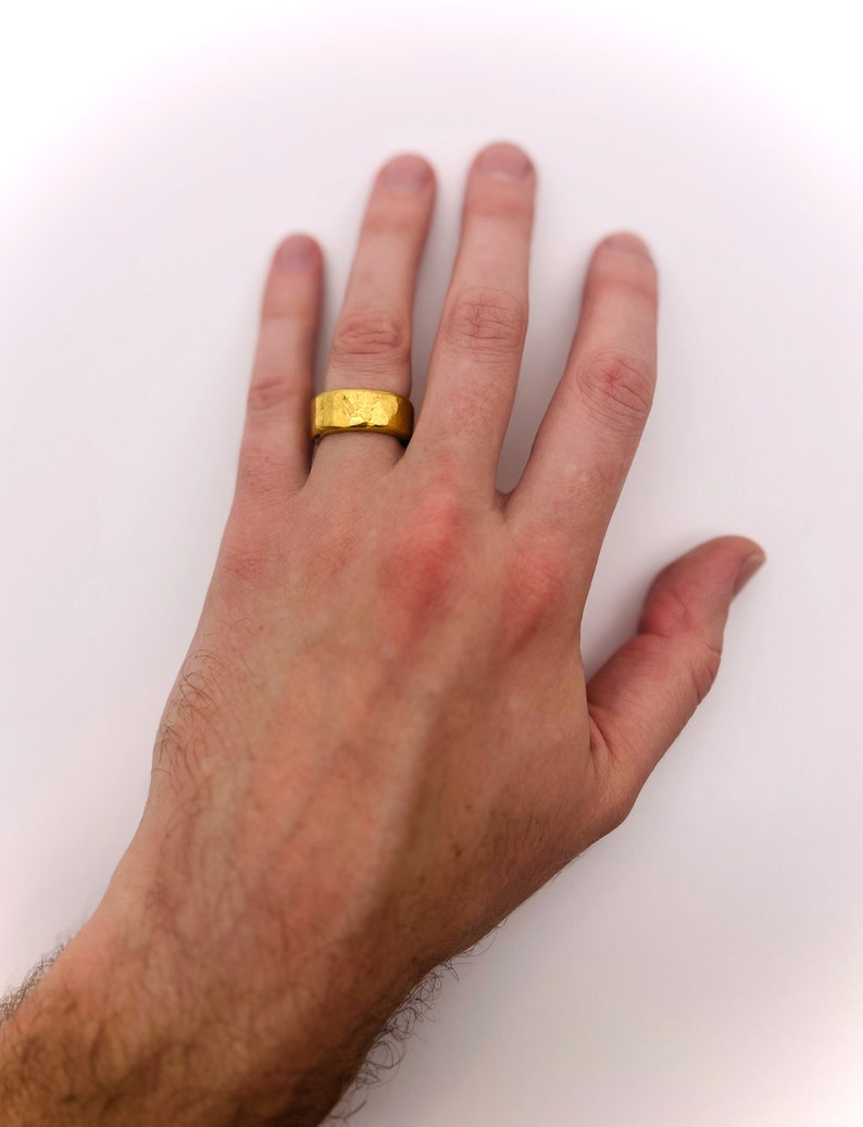 May include: A gold band ring with a textured surface.