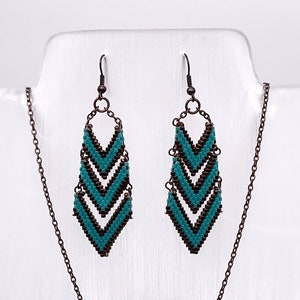 May include: A turquoise and copper necklace and earrings set with a chevron pattern. The necklace has a long chain and a pendant with three stacked chevrons. The earrings have a single chevron dangle.