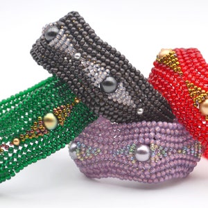 May include: Four beaded bracelets in different colors, including green, purple, red, and black. Each bracelet has a unique pattern and features pearl-like beads.