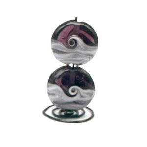 May include: A decorative, handcrafted bead ornament. Two round, dark purple and gray glass beads are stacked, each with a swirling wave design. The ornament sits on a wire base, creating a unique, artistic piece.