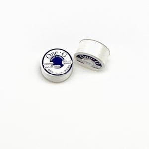 May include: Two spools of white nylon thread with blue labels that say "One-G" and "Made in Japan".
