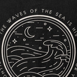 Op de afbeelding: Zwart grafisch ontwerp met een cirkelvormige illustratie van oceaangolven, een halve maan, sterren en de tekst "THE WAVES OF THE SEA IS HIS STORY". Het ontwerp is in wit op een zwarte achtergrond, wat een opvallend contrast cre&euml;ert.