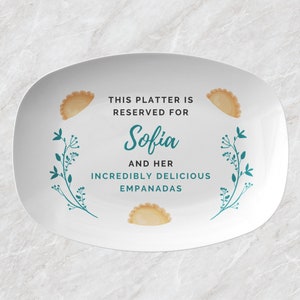 May include: White oval platter with text that reads "THIS PLATTER IS RESERVED FOR Sofia AND HER INCREDIBLY DELICIOUS EMPANADAS." The platter has illustrations of empanadas and teal floral accents.