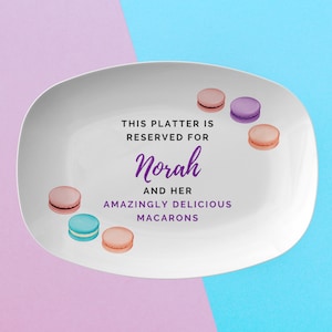 May include: White, oval platter with a purple and teal background. The platter is decorated with watercolor macarons in various colours. Text on the platter reads "THIS PLATTER IS RESERVED FOR Norah AND HER AMAZINGLY DELICIOUS MACARONS."