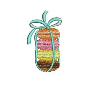 Peut inclure: Une pile de quatre macarons colorés liés ensemble par un ruban bleu clair. Les macarons sont disposés de bas en haut : marron, jaune, rose et orange.