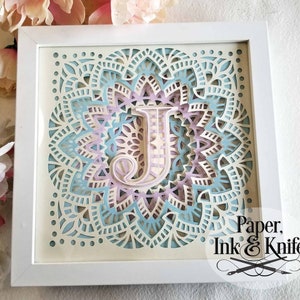Beautiful intricate multi layered shadowbox DIY template. All letters of the alphabet included in this digital file download.
The letter J is depicted in colors of blue, lavender and white. A white shadowbox frame shows how lovely this will be.
