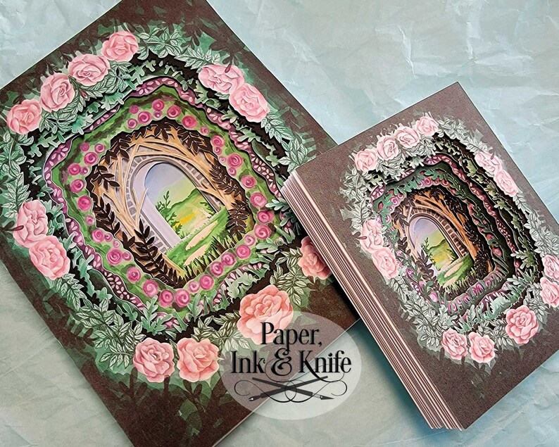 May include: Two paper art pieces featuring a layered design of a garden archway, surrounded by pink roses and green foliage. The artwork has a dark brown background. The text "Paper, Ink & Knife" is visible in the lower right corner.