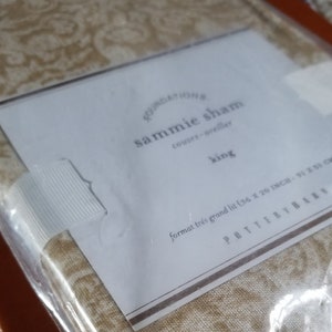 May include: A white and gold patterned king-size sham with the text "FOUNDATIONS sammie sham couore-oreiller king format trés grand lit (36 x 20 INCH. 91 x 51 CM) POTTERY BARN" on the label.