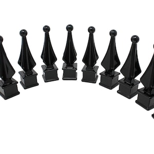 May include: Ten black metal fence finials with a pointed top and a square base.