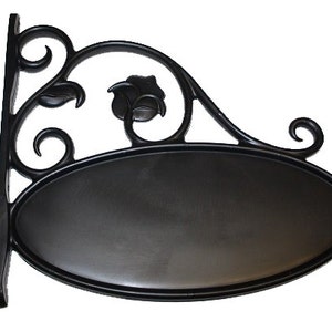 May include: Black metal sign holder with a scrolled design and a floral accent. The holder has an oval-shaped sign with a blank surface.