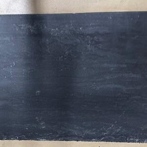 May include: A dark gray rectangular slate tile with a smooth surface and subtle veining.