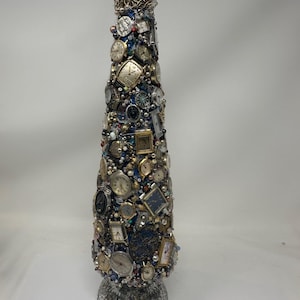 K&ouml;nnte beinhalten: Ein silberner und blauer Weihnachtsbaumschmuck, der mit Dutzenden von Vintage-Analog-Armbanduhren verziert ist. Der Baum ist mit einer goldenen Kette und Perlen gekr&ouml;nt.