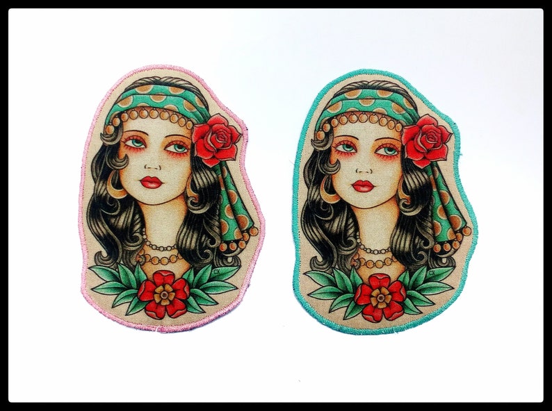 May include: Two embroidered patches featuring a vintage-style portrait of a woman with long black hair, a headscarf, and a red rose. One patch has a pink border, the other has a teal border. Both have a red flower at the bottom.