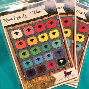 Könnte beinhalten: Ein farbenfrohes Quiltmuster mit einem Patchwork aus Schafen mit schwarzen Augen und einer Vielzahl von Farben, darunter Rot, Orange, Gelb, Grün, Blau, Lila und Weiß. Der Quilt trägt den Titel "Have ewe any wool?" und wurde von Mauve Bandit hergestellt.