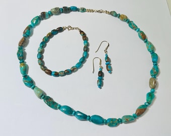 May include: A turquoise gemstone jewelry set, including a necklace, bracelet, and earrings. The necklace and bracelet are strung with oval-shaped beads in shades of turquoise and brown. The earrings feature a similar design, with turquoise and brown beads.