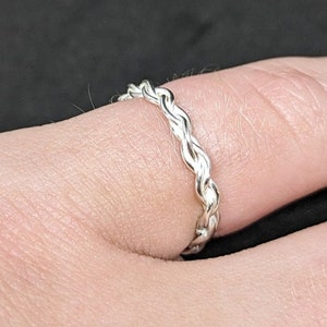 May include: A silver braided ring worn on a finger.