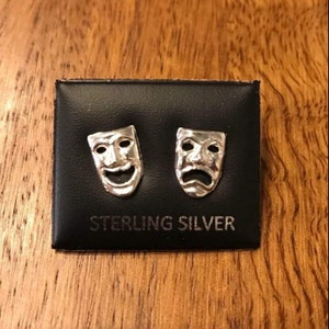 Puede incluir: Un par de pendientes de plata de ley con un diseño de máscara de rostro feliz y triste.