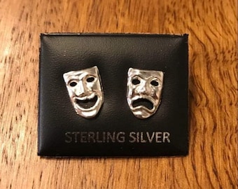 May include: A pair of sterling silver earrings featuring a happy and sad face mask design.