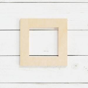 May include: A light wood picture frame with a simple design. The frame is on a white wood background.