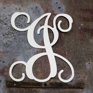 May include: White metal letter S with a decorative script font. The letter is mounted on a rustic metal background.