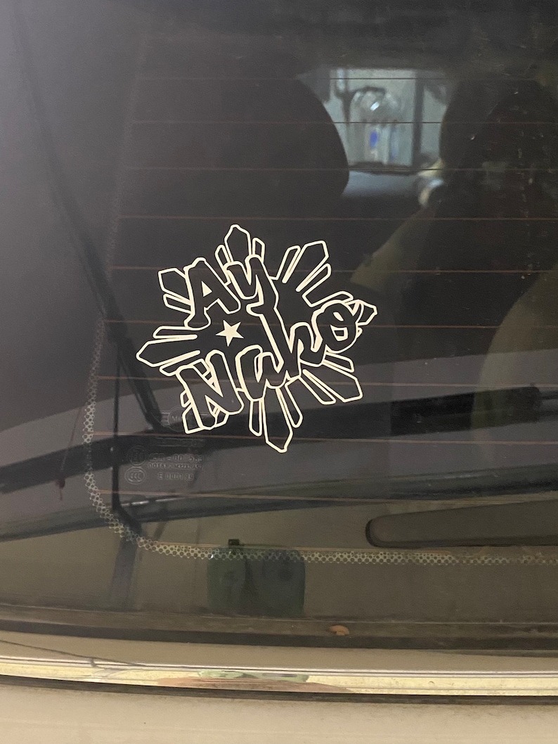A white vinyl decal on a black car window with the Filipino flag star design and the words 'Ay Nako' in a stylized font.