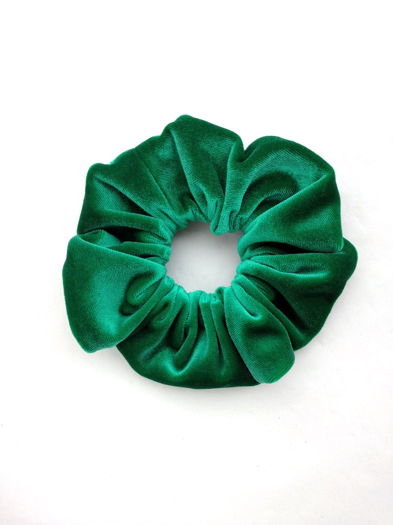 Pu&ograve; includere: Un'elastico per capelli in velluto verde brillante, un accessorio per capelli, &egrave; mostrato su uno sfondo bianco. L'elastico &egrave; circolare, con un design in tessuto arricciato. Il materiale morbido aggiunge consistenza e un tocco di lusso all'elastico per capelli.