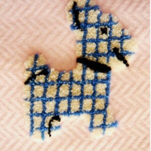 May include: A tufted dog design in blue and cream, with a black collar and accents, is set against a pink herringbone background. The dog's body is a grid pattern, creating a textured, handcrafted appearance. The overall aesthetic is soft and playful.