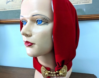 May include: A red velvet hood with a gold metal clasp. The hood is worn on a mannequin's head.