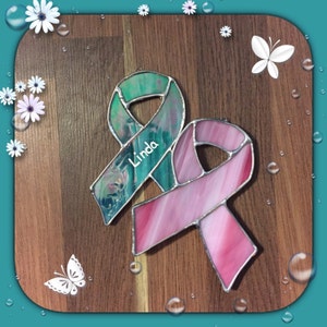May include: Two glass ribbon ornaments, one pink and one green, with the name "Linda" inscribed on the green ribbon.