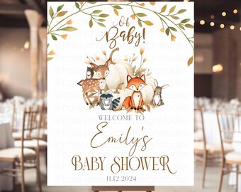May include: A rectangular sign on a wooden easel featuring the text Oh Baby! Welcome to Emily's Baby Shower 11.12.2024. The design includes watercolor illustrations of a deer, fox, raccoon, and rabbit sitting among white pumpkins and autumn leaves.