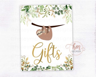 May include: A white sign with a gold border and green foliage around the edges. A sloth and baby sloth are hanging from a branch. The text "Gifts" is written in gold cursive lettering. The sign is for a baby shower.