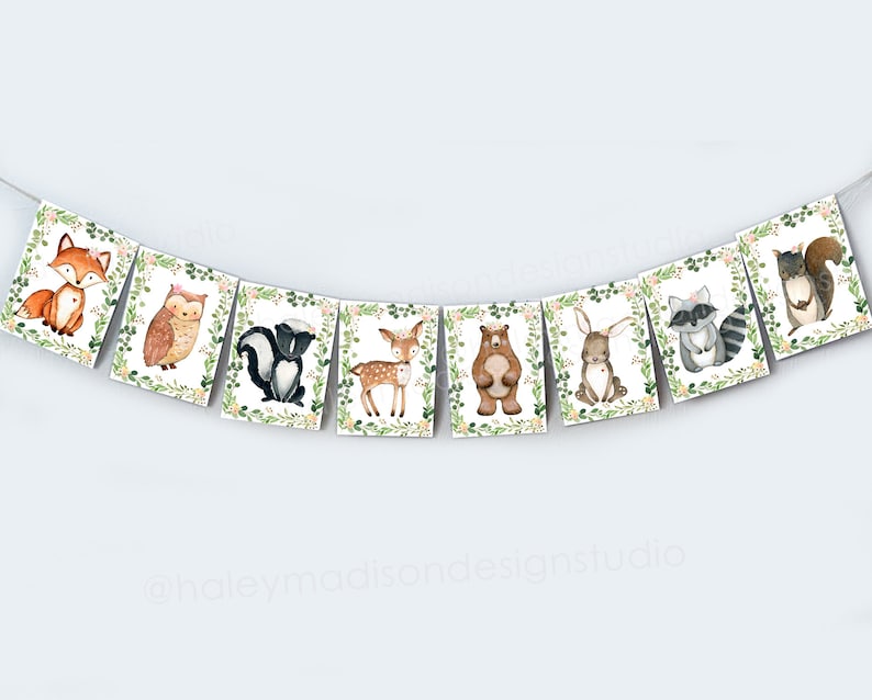 May include: A woodland animal banner with a fox, owl, skunk, deer, bear, rabbit, raccoon, and squirrel. Each animal is surrounded by green leaves and pink flowers.
