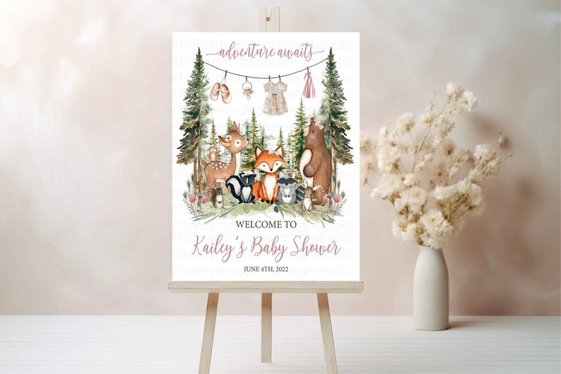 K&ouml;nnte beinhalten: Ein wei&szlig;es Schild mit Waldmotiv f&uuml;r eine Babyparty. Das Schild zeigt ein Reh, einen Fuchs, einen B&auml;ren, einen Waschb&auml;ren und andere Waldtiere. Der Text auf dem Schild lautet "adventure awaits" und "Welcome to Kailey's Baby Shower June 4th, 2022".