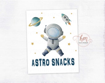 May include: A watercolor illustration featuring an astronaut in a spacesuit, a planet with rings, and a rocket ship. The words "ASTRO SNACKS" are printed in navy blue. Gold stars are scattered around the astronaut and celestial objects.